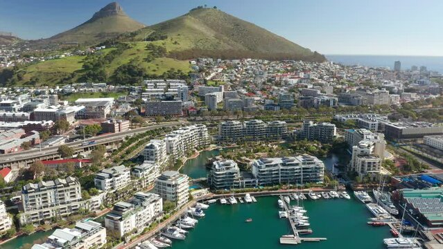 An aerial shot flying towards the marina island in Cape Town's Waterfront with the famous Lion's Head mountain in the far background.