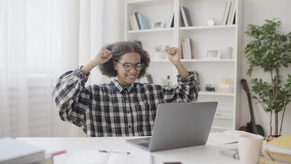 Female student successfully finishing school project, raising hands in joy, online education