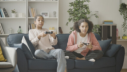 Joyful teenagers enjoying video game at home, sitting on the sofa, leisure