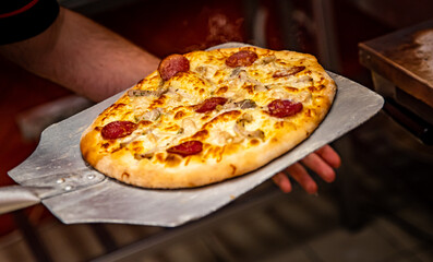 chef baker making pizza at kitchen. Put on landing shovel and send it to the oven.