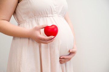 Side view of a Pregnant woman holding heart.Motherhood and pregnancy concept