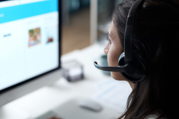 Fully skilled in providing quality customer support. Shot of a young woman using a headset and...