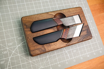 Exclusive handmade leather craft tools. Set of knifes from steel and wood. Close up of different tanner tools on wooden box. 