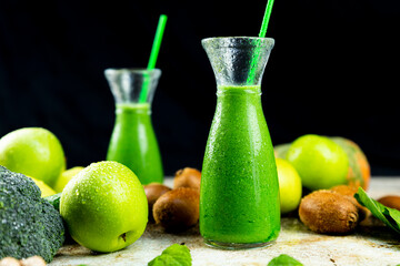 Healthy green smoothies with spinach, apple, kiwi, broccoli and mint in glass jar with fruits and vegetables on the wooden table. Detox and healthy concept