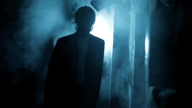 Cinematic shot of a man in a suit walking in dramatic lighting and some fog around him. Dark shot of a man walking. High-resolution footage.
