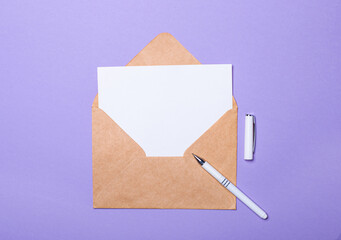 On a purple background, a white pen, a craft envelope and a white blank card with a place to insert...