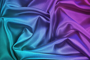 Pink tuquoise silk satin. Gradient. Wavy folds. Shiny fabric surface. Beautiful purple teal background with space for design. 