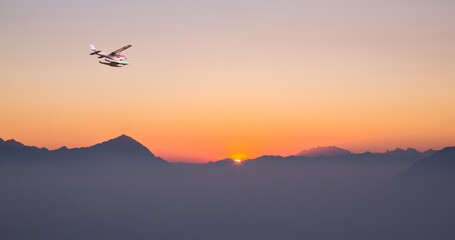Fototapeta na wymiar seaplane in flight at sunset over the alps
