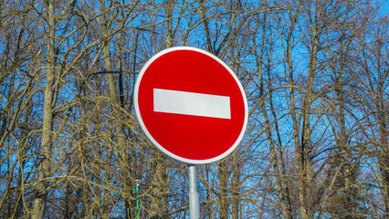 A red round sign warns: entrance forbidden. It is a one way street. In the background a tree. No...