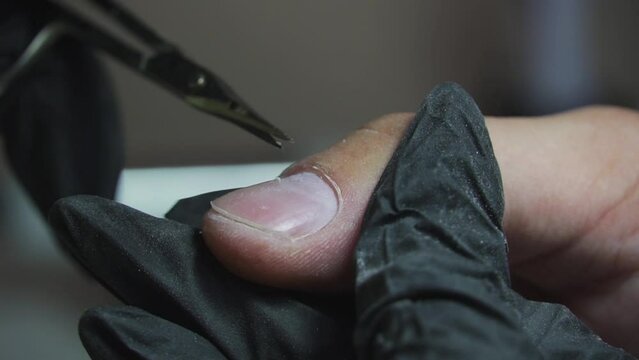 Manicurist cuts cuticles on male hands