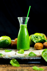 Healthy green smoothies with spinach, apple, kiwi, broccoli and mint in glass jar with fruits and vegetables on the wooden table. Detox and healthy concept
