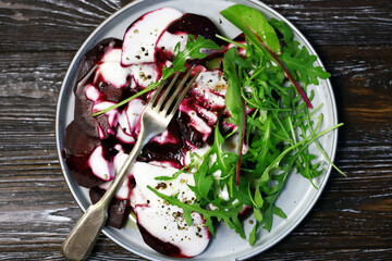 Selective focus. Macro. Vegan food. Beetroot arugula salad on a plate with yogurt sauce and olive oil. Healthy food. Diet salad.