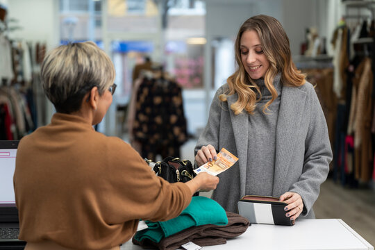 Young blonde woman paying in cash at the clothing store with a fifty euro bill