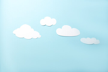 Paper art. White clouds on a bright blue background. Flat lay