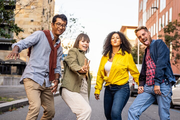 Multiracial group of friends having fun walking in a foolish way by street, party mood, happy university students acting funny moves and steps, smiling young people dancng in the city street - Powered by Adobe