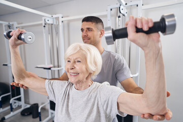 Male orthopedic surgeon doing dumbbell exercise with elderly lady