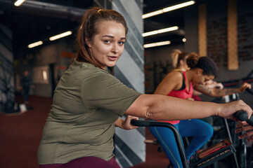 Fototapeta na wymiar Girl exercise on orbitrek with girlfriends in gym