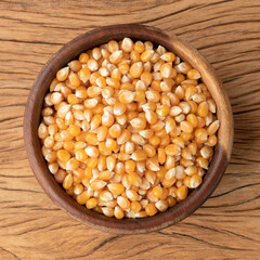 Dried corn or popcorn grains in a bowl over wooden table