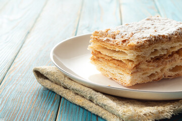 Napaleon cake on a white dish wooden background