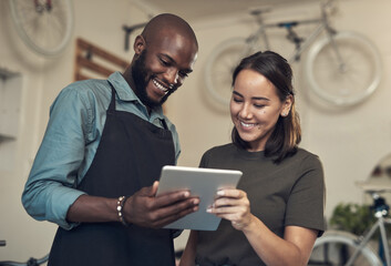 Can you help me find this bike. Shot of two young colleagues standing together in their bicycle shop and using a digital tablet.