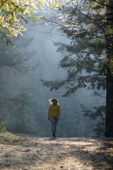 Woman makes a light jog through the misty forest in the morning, dawn and foggy morning in the woods.