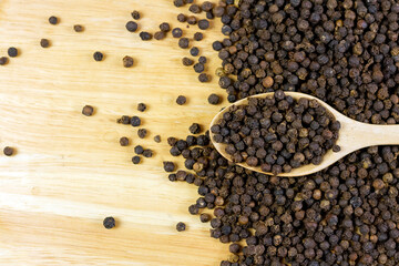 Black pepper on wooden spoon on wooden background. Black pepper is a spicy seasoning and herb for healthy.
