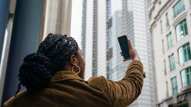 Woman using phone to take selfie in city