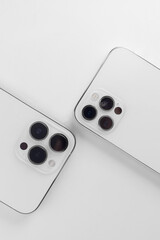 white smartphones on a white background lie with the cameras up. Iphone 12 pro, iphone 13 pro max