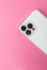 white phone with three cameras on a pink background. Iphone 13 pro max