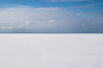 Blurred image of a frozen river covered with snow and clouds against a blue sky. Minimalism.