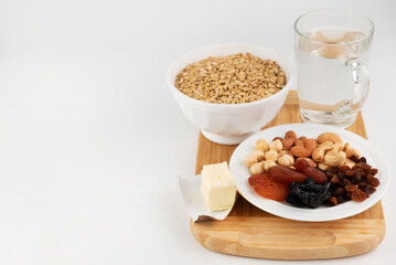 On a white background, a blurred image of the ingredients for making oatmeal with dried fruits and nuts.