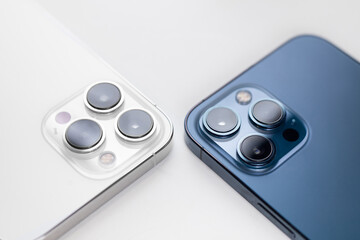 white and blue smartphone lies with cameras up on a white background - obrazy, fototapety, plakaty