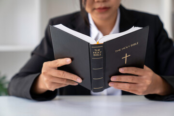 Christian woman holds bible in her hands. Reading the Holy Bible in a field during beautiful sunset. Concept for faith, spirituality and religion