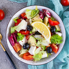 Fresh salad with tomato, lettuce, avocado, olives, feta and pepper. Diet eating