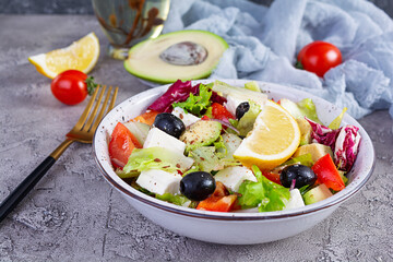 Fresh salad with tomato, lettuce, avocado, olives, feta and pepper. Diet eating