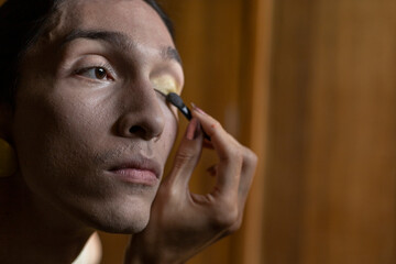 A transgender young man (22) is in his room putting on makeup. Concept of transgender