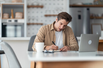 Middle-aged man taking a notes while following an online course.