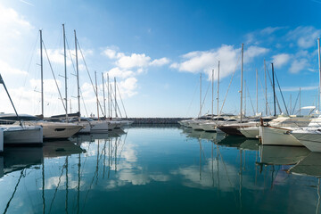 Fototapeta na wymiar Marina with boats reflected on the sea and blu sky with white clouds