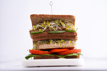Tasty vegan sandwiches with whole brown protein bread, tofu cheese, tomato, spinach and microgreens...