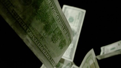 One hundred dollar bills falling down. Slowmotion of falling dollars on black background. 