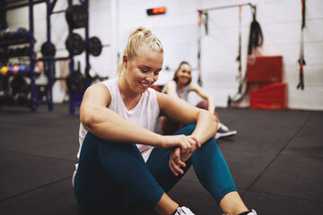 Smiling woman resting on a gym floor after a workout