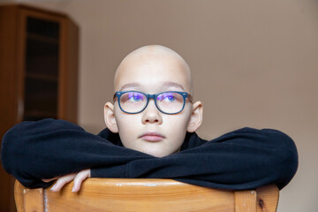 portrait of depression sad bald young teen girl with cancer after chemotherapy. wearing glasses and...