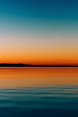 A colorful sunset over the sea with the mountains on the horizon