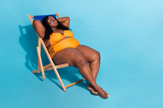 Full length photo of obese large lady enjoy resort lie deckchair sun bathing isolated over blue color background