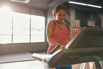Fototapeta na wymiar Black girl push button on treadmill while run