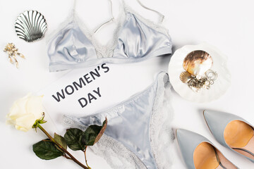 Top view of lingerie, card with womens day lettering and heels on white background