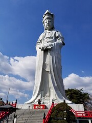 Byakue Kannon Among Blooming Japanese Cherry Blossoms Sakura and Magnolia under Blue Sky