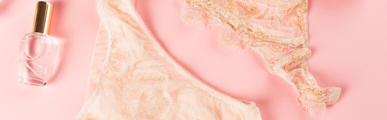 Top view of peach lingerie near perfume on pink background, banner