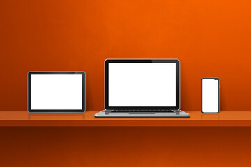 Laptop, mobile phone and digital tablet pc on orange wall shelf. Horizontal background