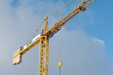 A lonely yellow tower crane on the sky background